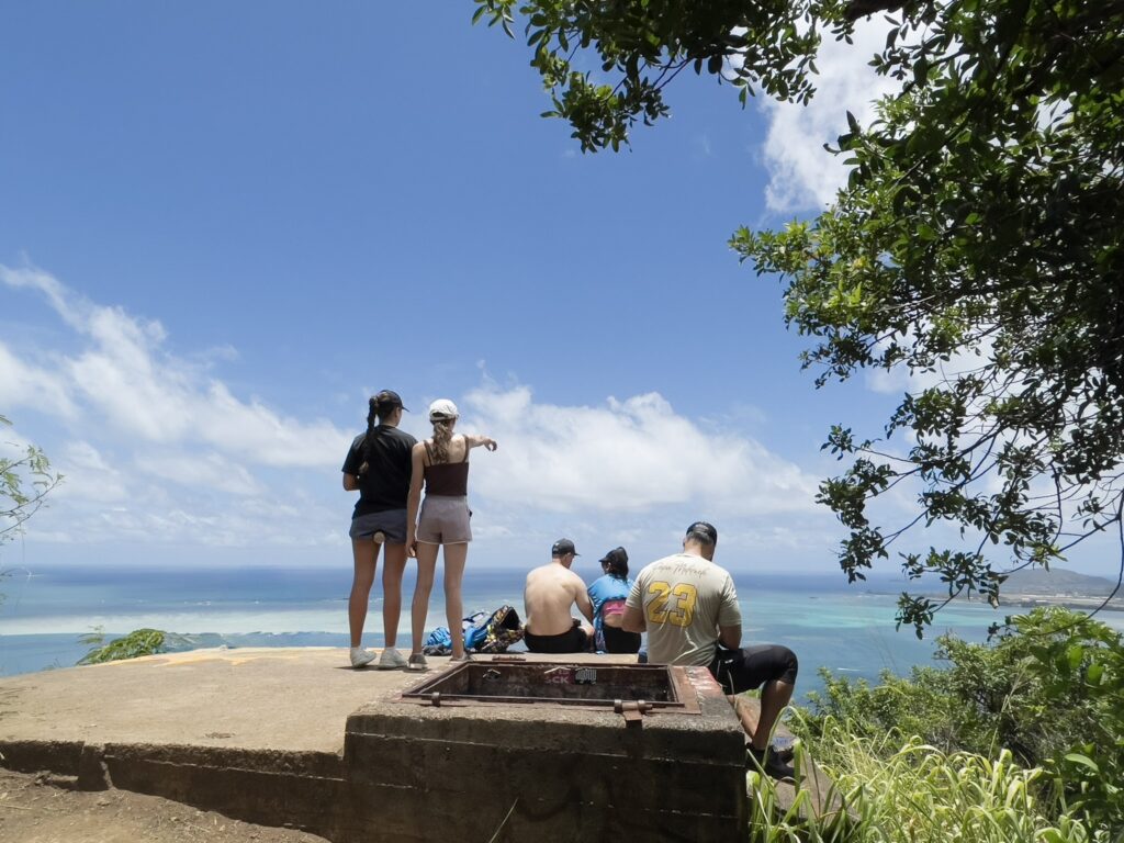 プウ・マエリエリ・トレイルから見渡すカネオヘ湾。展望ポイントで景色を眺めるハイカーの姿が見える。