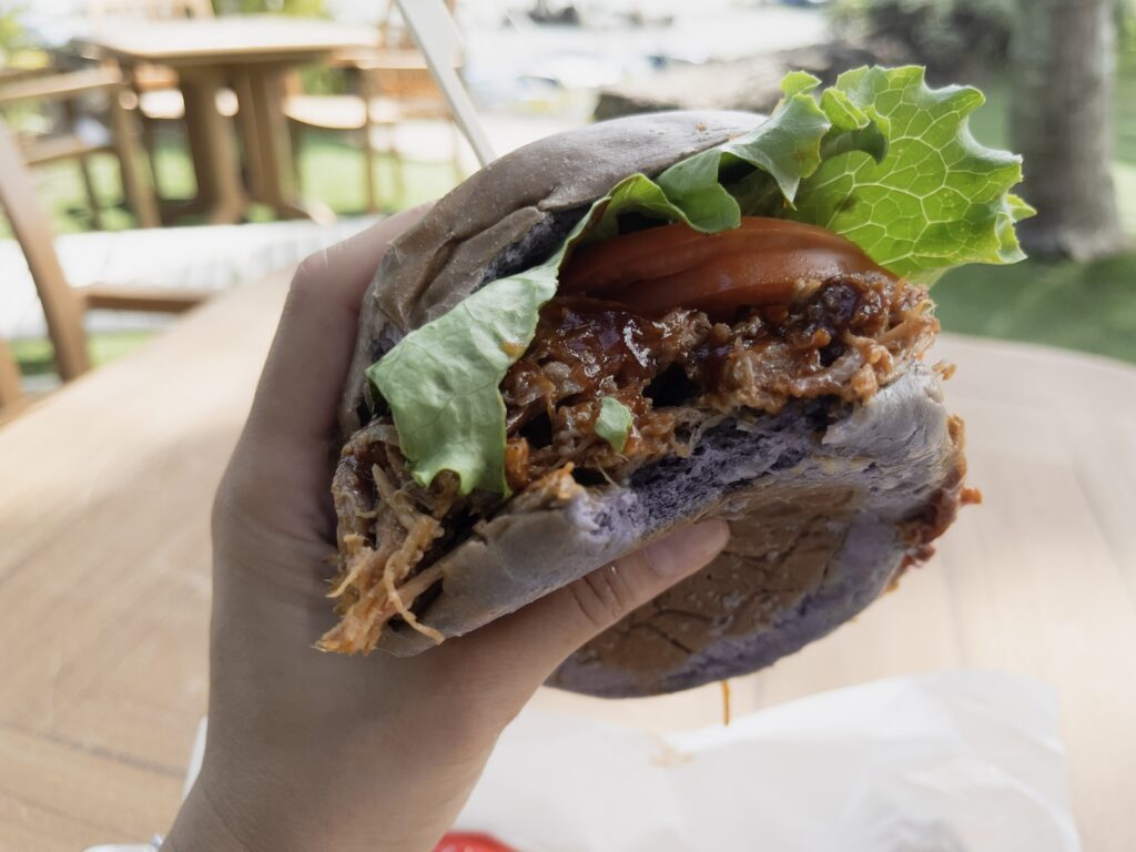 クアロア・ランチのテラスで、ランチのハンバーガー クアロア・ランチのテラスで食べるハンバーガー。かじった断面と背景のテーブル席