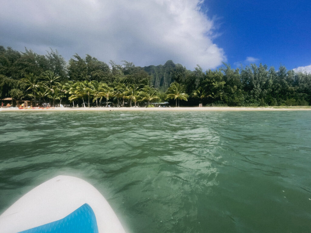 海に浮かぶSUPの先端越しに、遠くコオラウ山脈を望む風景